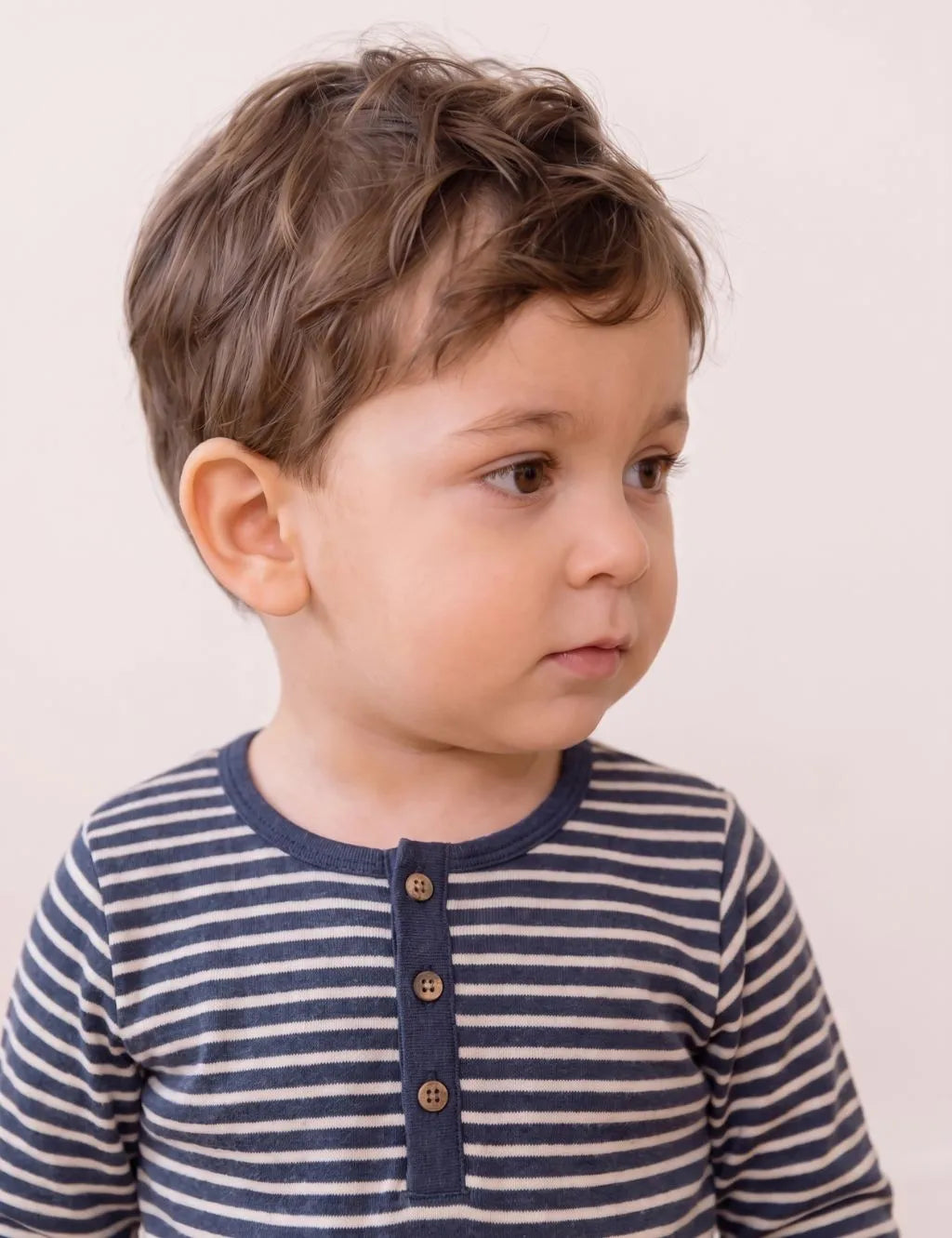 Close-up portrait of a toddler wearing an organic cotton navy and white striped long-sleeve polo shirt