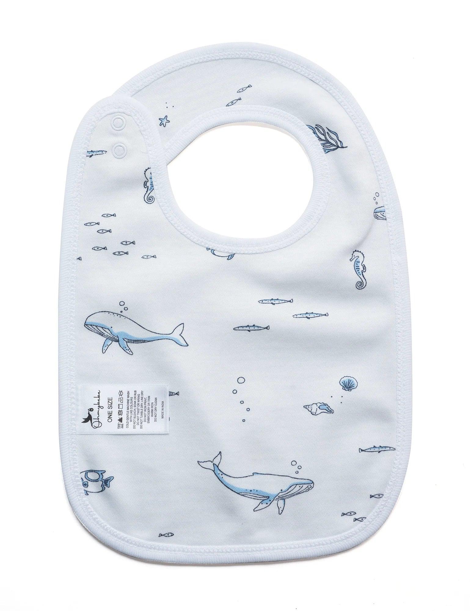 White organic cotton baby bib with blue ocean animal prints including whales, seahorses, fish, and shells