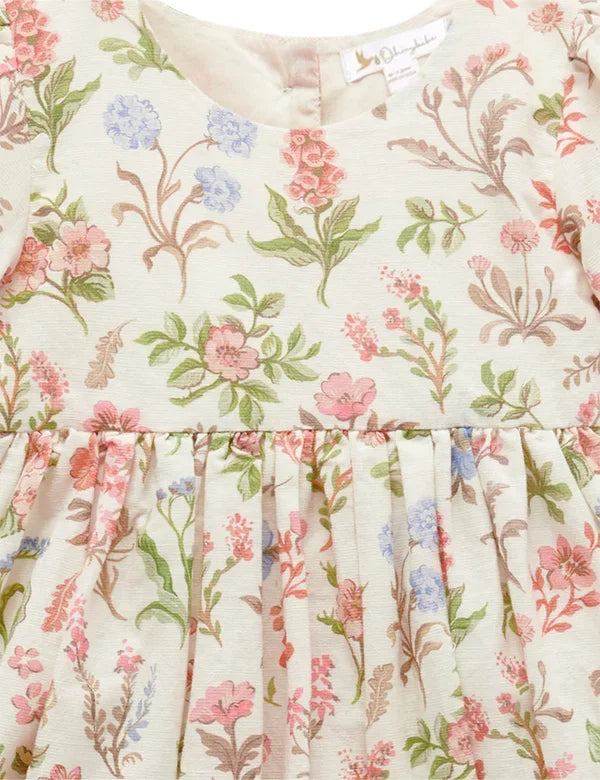 Close-up of organic cotton baby dress with pastel floral print featuring pink, green, and blue flowers