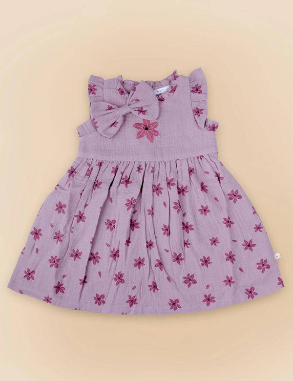 A delicate lilac organic cotton baby dress with a charming dark pink floral print and a matching oversized bow at the neckline. Shop sweet baby dresses India.