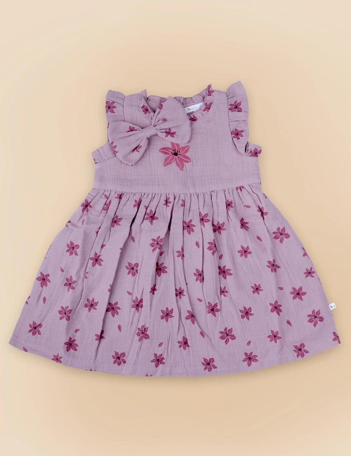 A delicate lilac organic cotton baby dress with a charming dark pink floral print and a matching oversized bow at the neckline. Shop sweet baby dresses India.