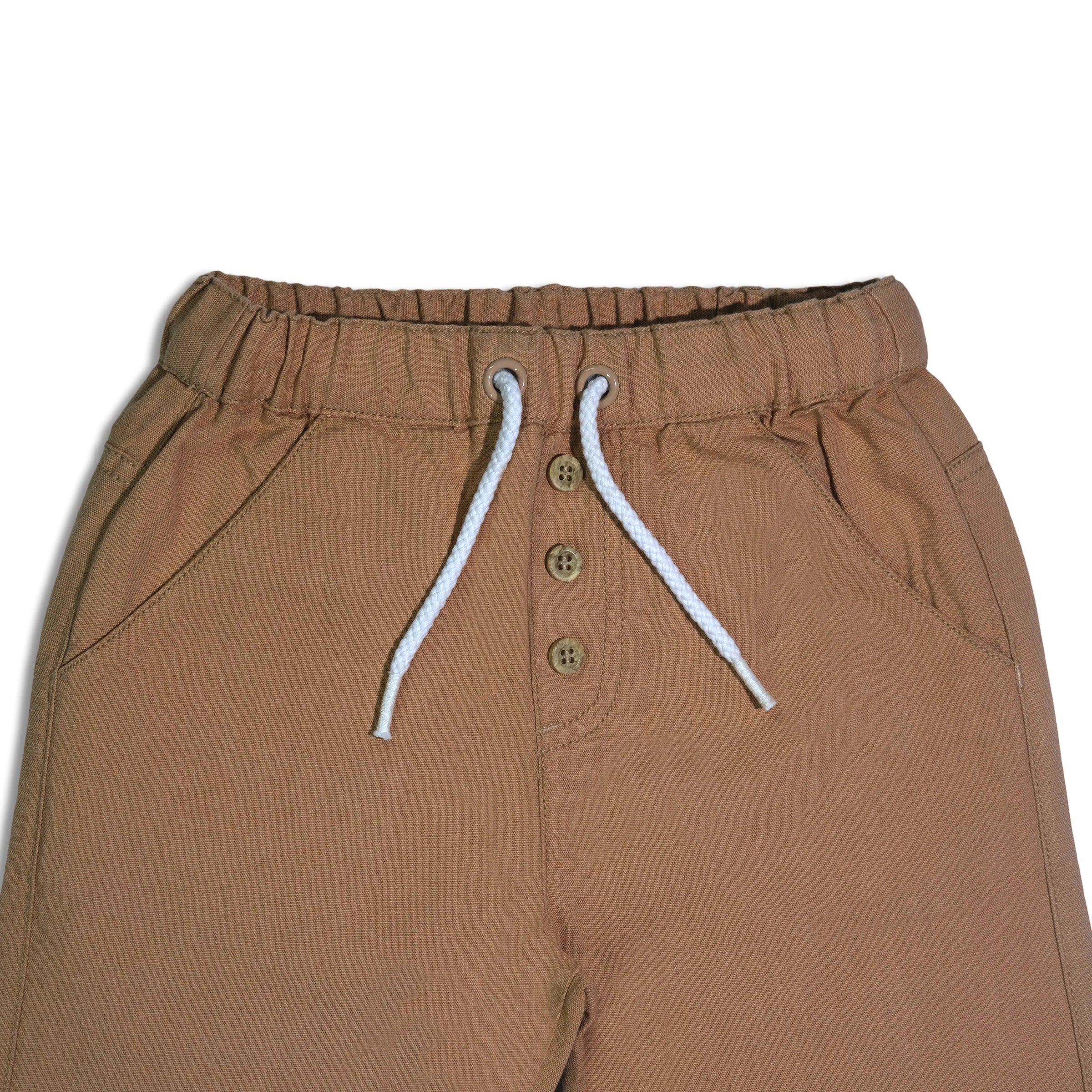 Organic cotton baby pants waist detail with elastic band, white drawstring, and beige buttons