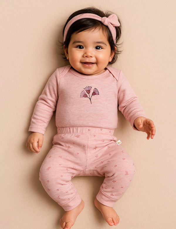 Adorable baby, who appears to be of South Asian descent, lying down wearing the complete 100% organic cotton Blossom Breeze 3-piece set. Shop online India.