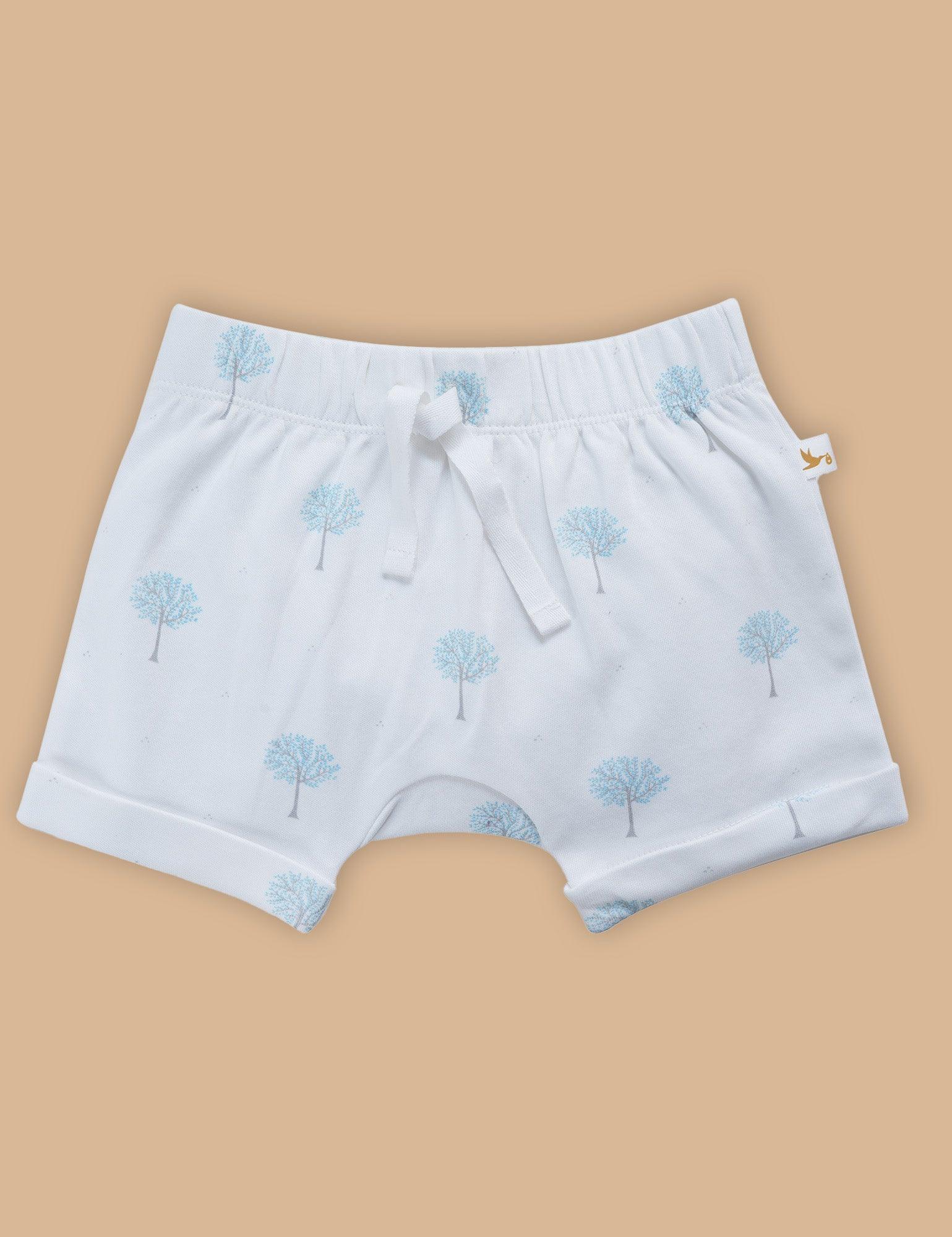 White organic cotton baby shorts with blue tree prints and drawstring on beige background