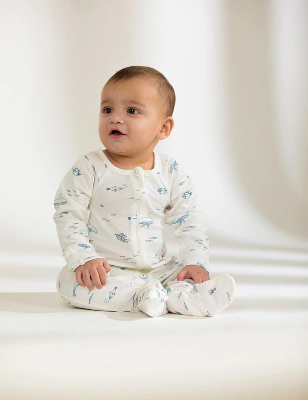 Adorable baby, who appears to be of South Asian descent, wearing a 100% organic cotton nautical print zip sleepsuit. Soft and safe for baby's comfort. Buy online India.