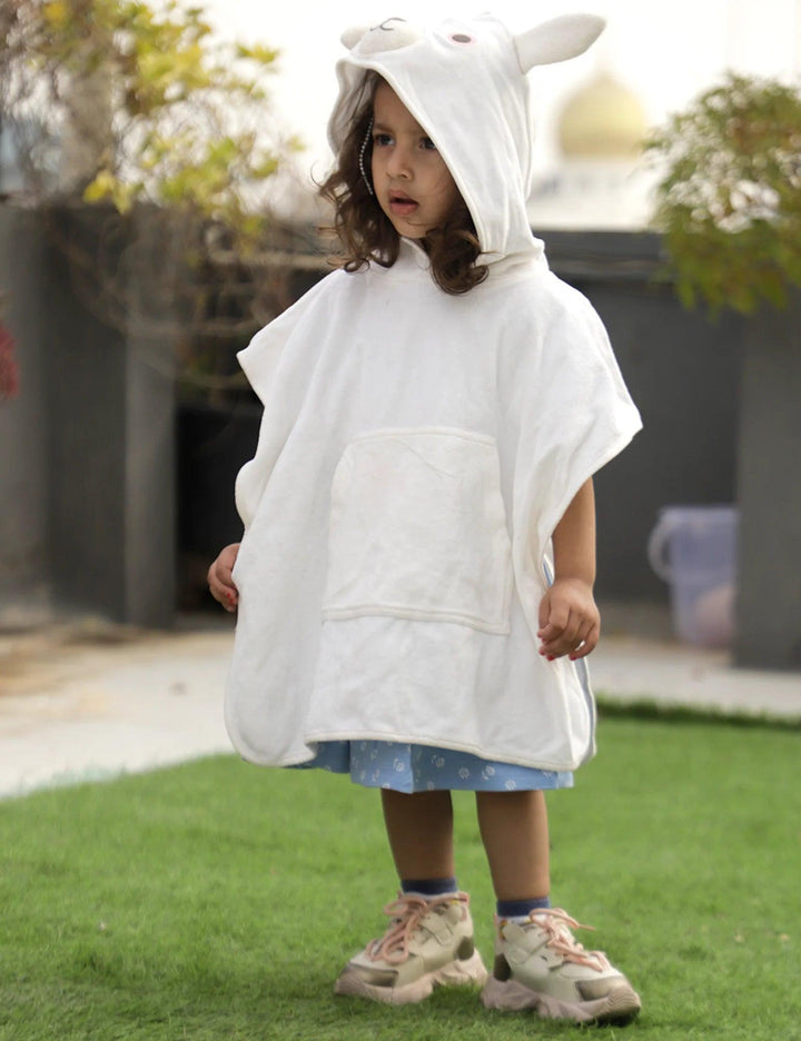 A young child, who appears to be of South Asian descent, wearing a soft white organic cotton hooded towel designed like a bunny with long ears. Shop gentle baby towels India.