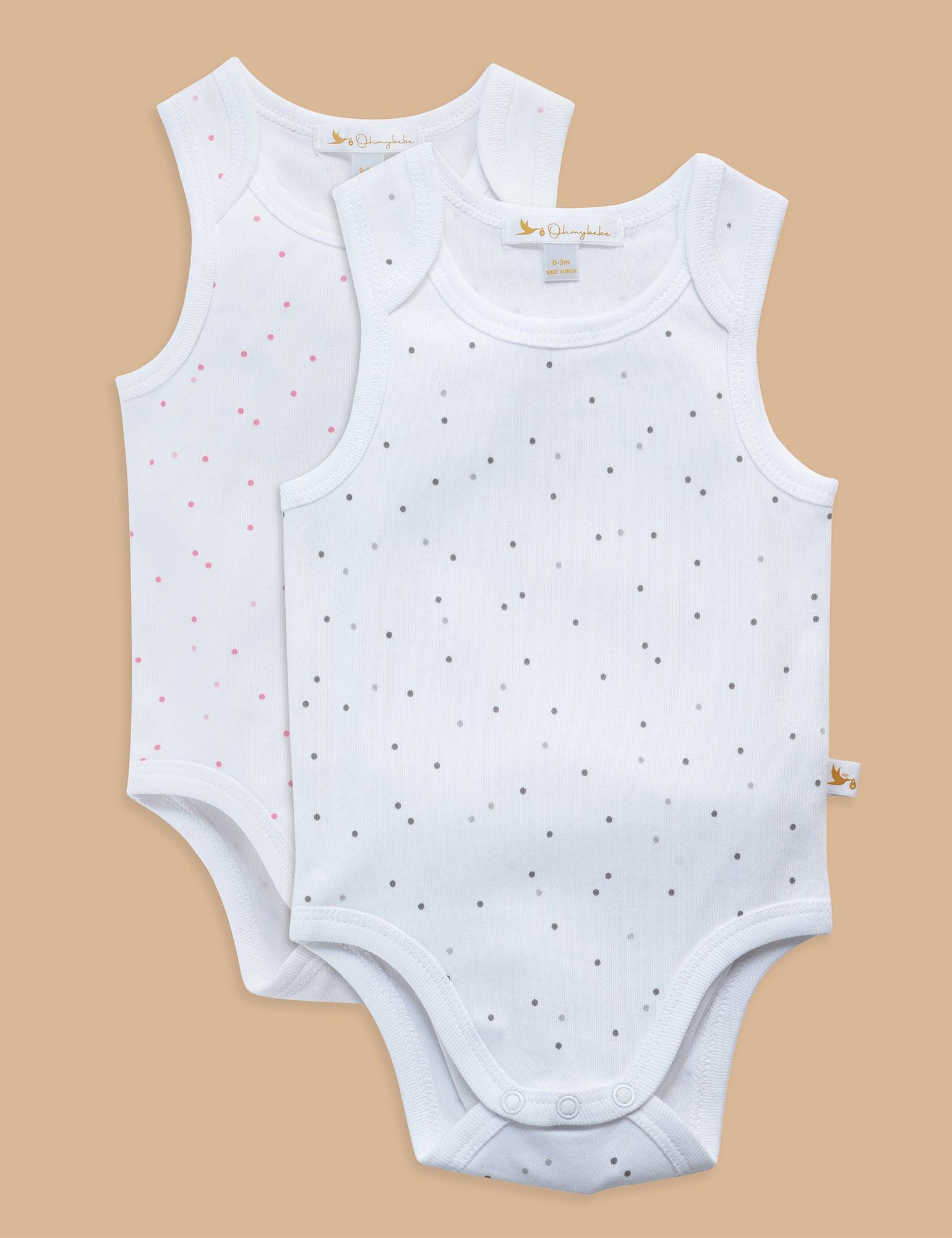 Two white sleeveless organic cotton baby bodysuits with gray and pink polka dots on beige background