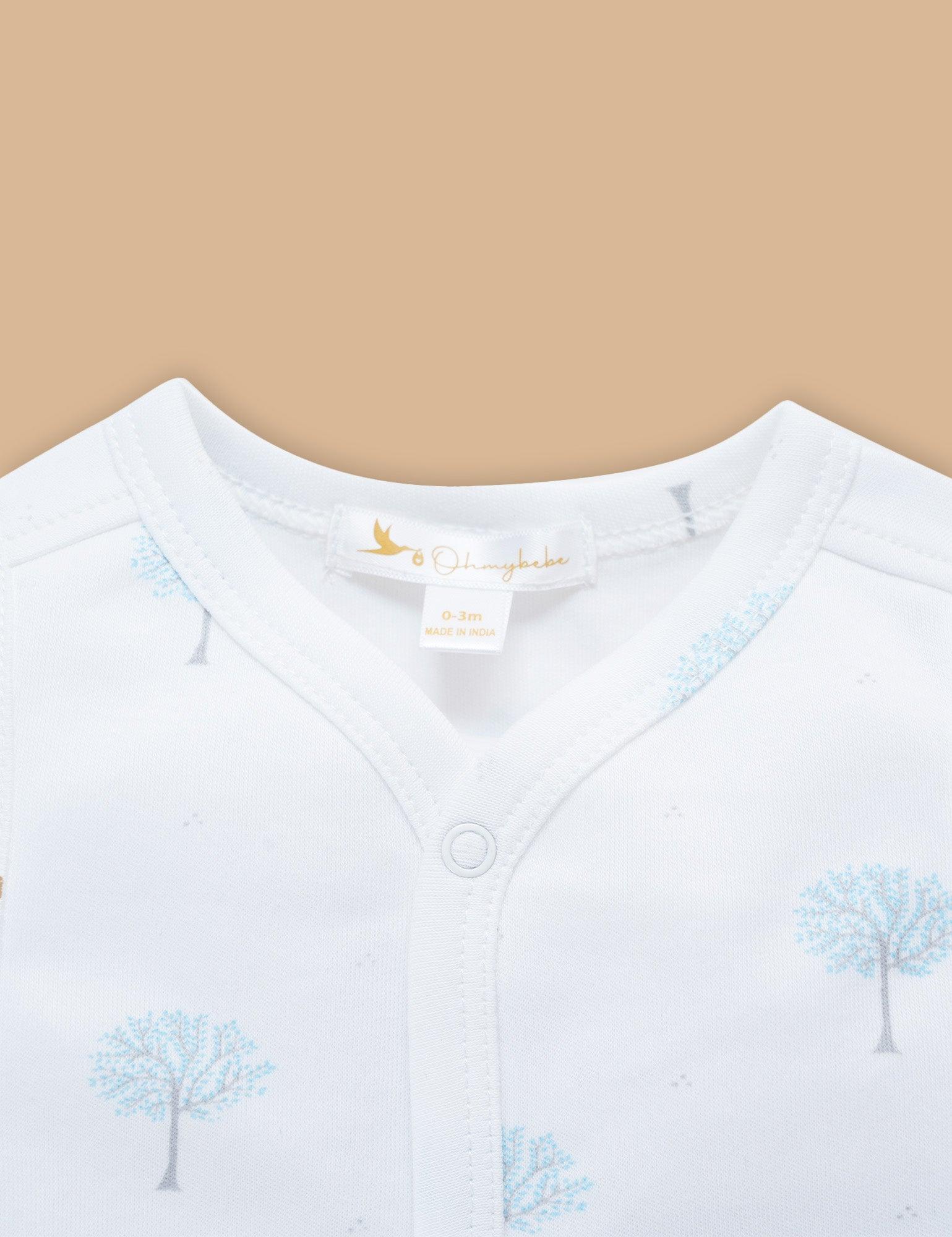 Close-up of white baby organic cotton top with light blue tree prints and front snap closure