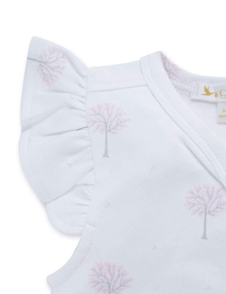  Close-up of the white organic cotton baby top showing the flutter sleeve and the subtle winter tree print. See organic baby wear India.