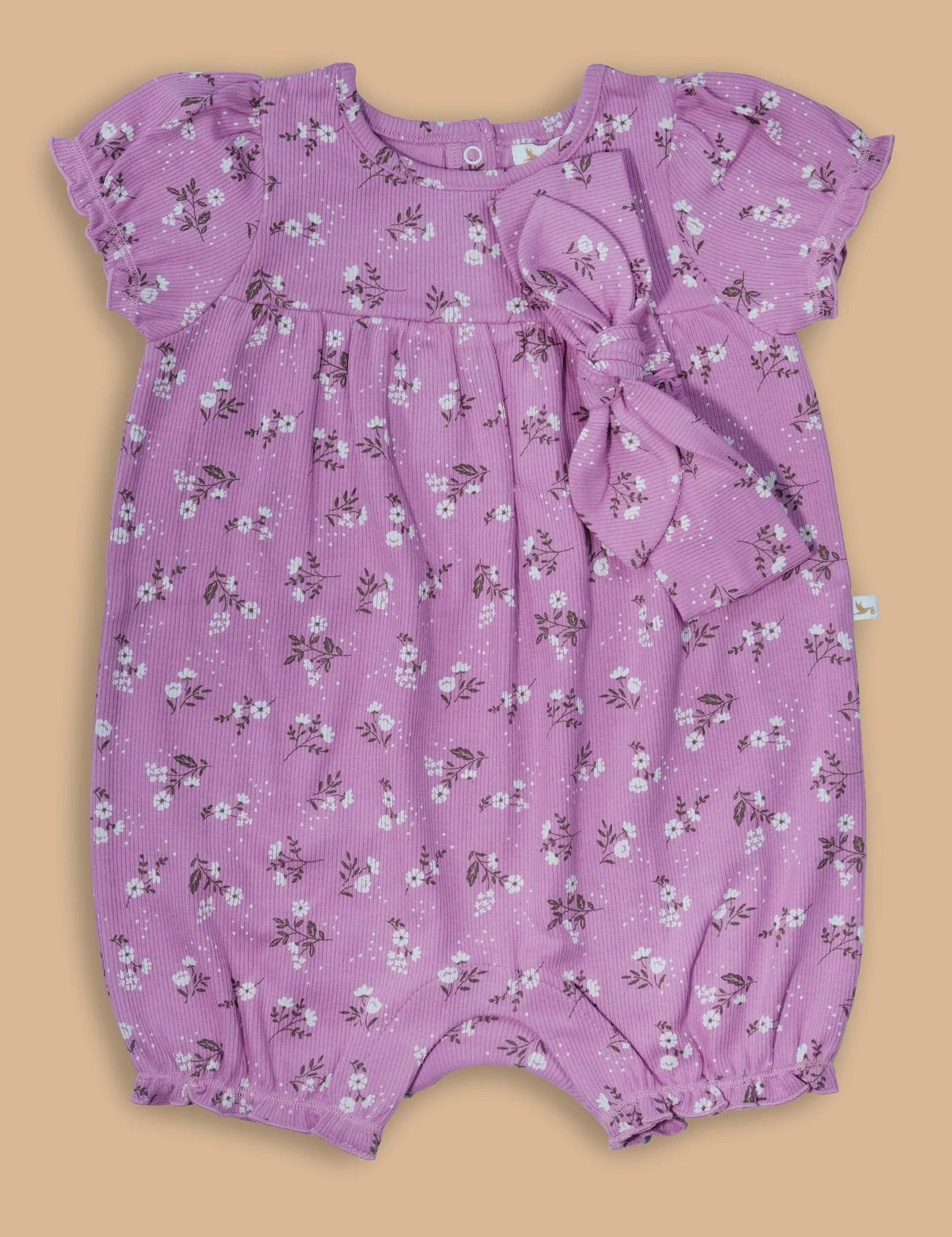 Lilac baby romper with white daisy print and matching bow headband on beige background