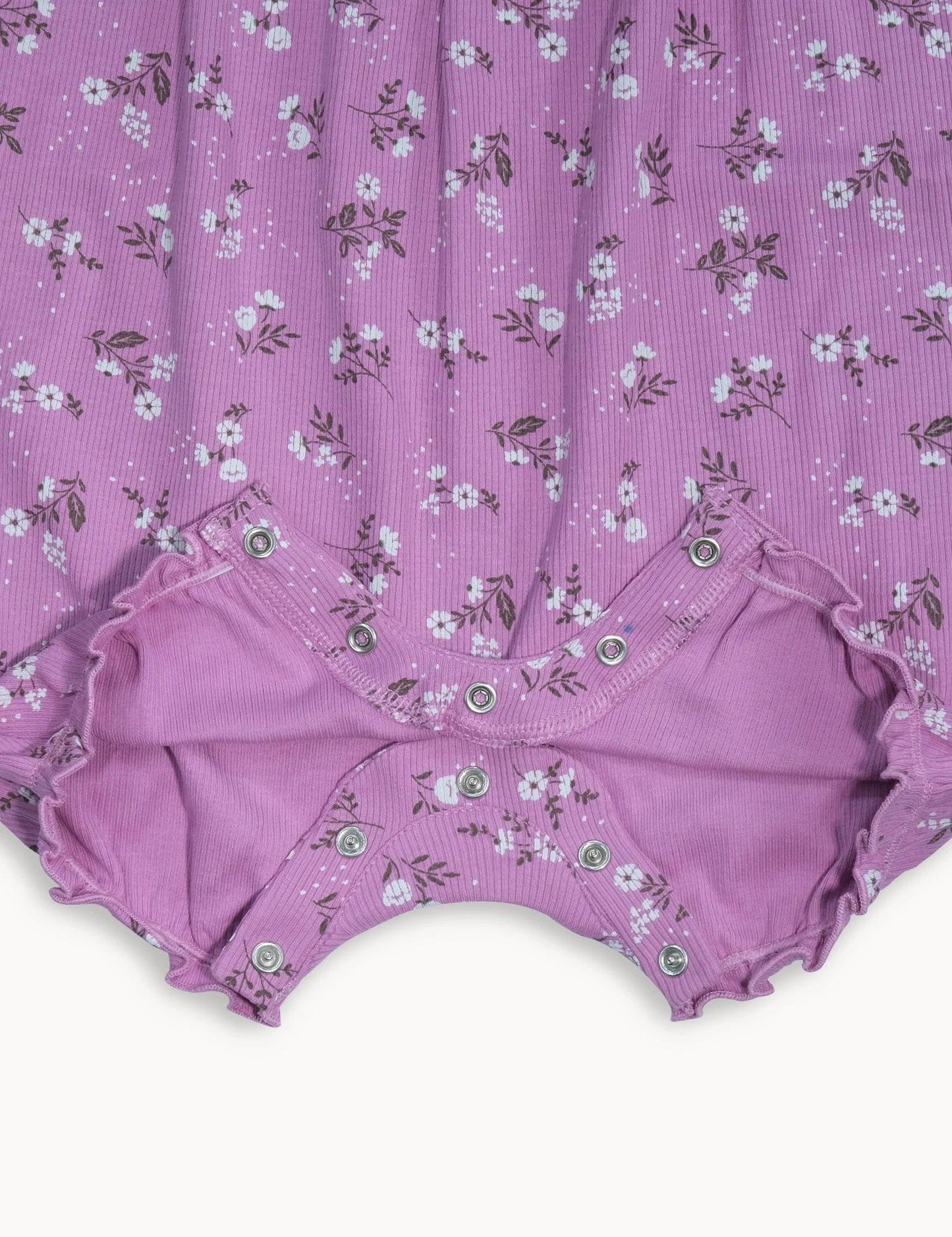 Close-up of organic purple baby romper with white daisy print and snap closures