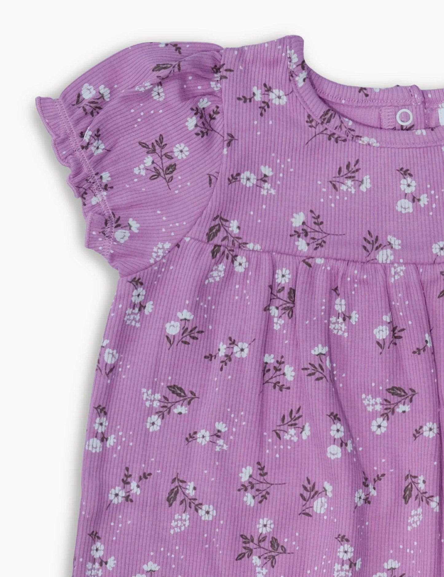 Close-up of purple baby romper with white daisy floral print and ruffled short sleeve