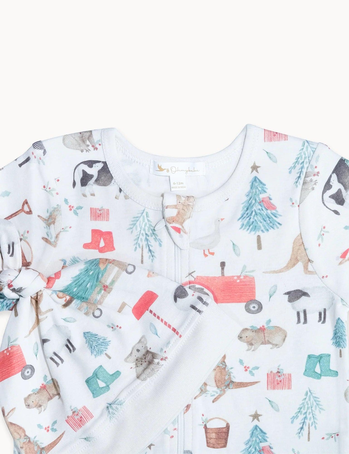 Close-up of white baby romper with organic farm animal print including cows, kangaroos, and trees