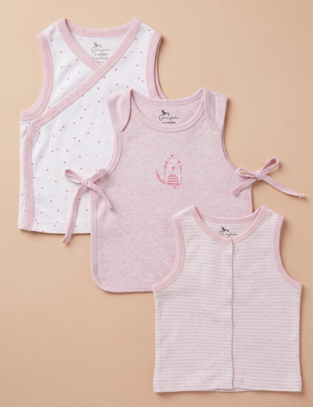 Flat lay view of three baby tank tops in a set. From back to front: a white wrap-style tank top with pink trim and small pink dots, a solid light pink tank top with side-tie closures and a cat graphic on the chest, and a sleeveless top featuring thin horizontal pink and white stripes with a front snap-button closure, all displayed against a plain beige background.