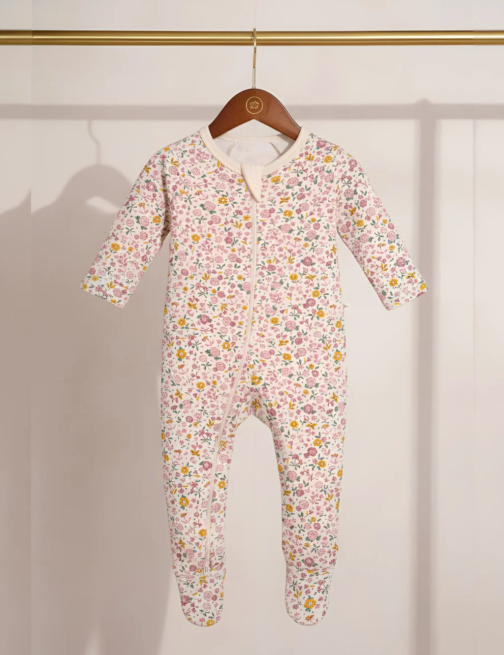 Floral-patterned baby onesie on a hanger against a white background