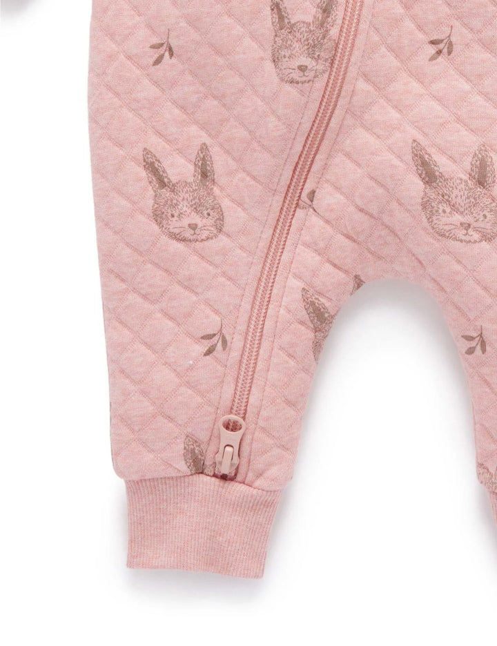 Close-up detail of a soft pink quilted baby jumpsuit showing the zipper closure and adorable bunny face and leaf prints on the fabric. Shop cozy baby clothing online India.