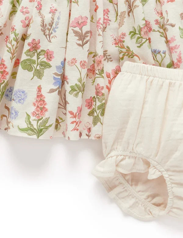 Baby girl's floral print dress with pastel colors and cream-colored ruffled bloomers