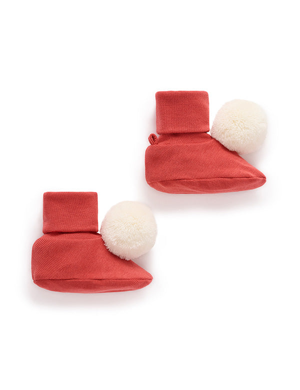 Red baby booties with white pom-poms on a white background