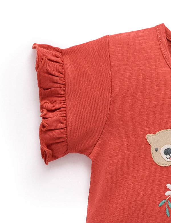 Red dress with ruffled neckline and bear patch on a white background