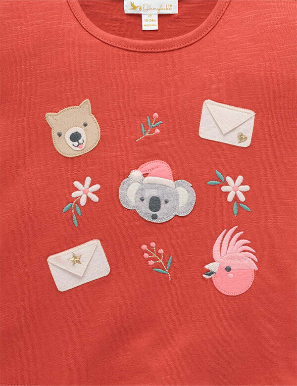 Red shirt with animal and floral appliqués on a plain background