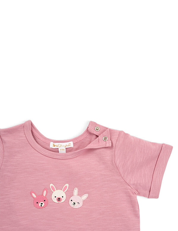 Close-up showing the practical shoulder snap closures on the pink organic cotton baby t-shirt