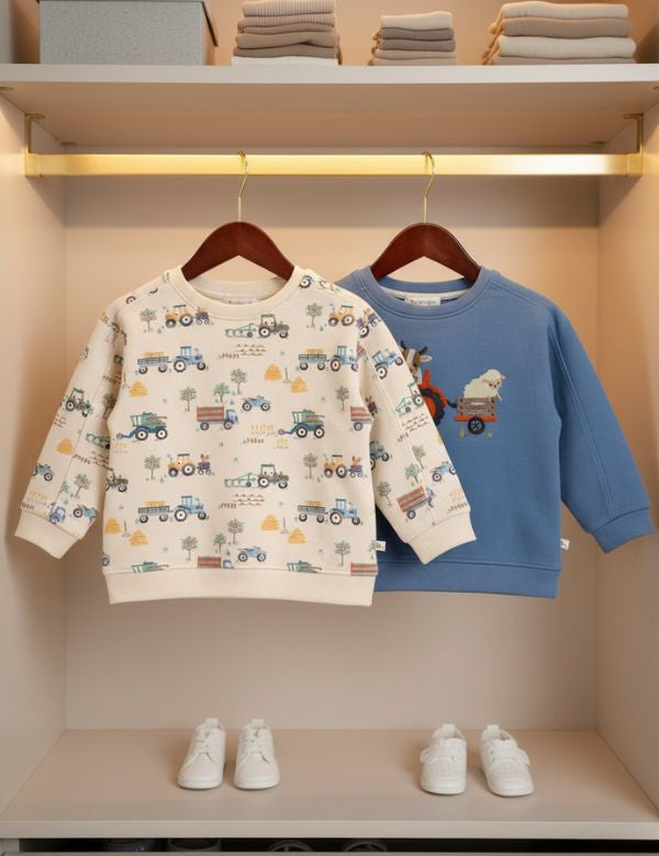 Kids winter sweatshirt set – blue tractor embroidered sweatshirt and cream farm print sweatshirt hanging on rack
