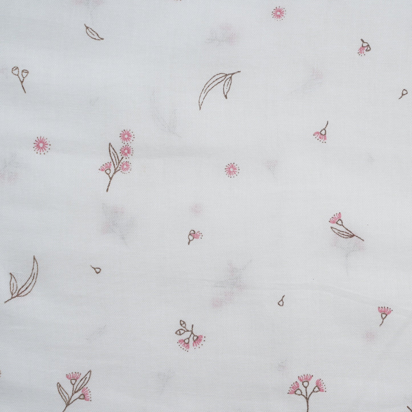White baby cap with delicate pink and brown floral pattern printed on lightweight fabric