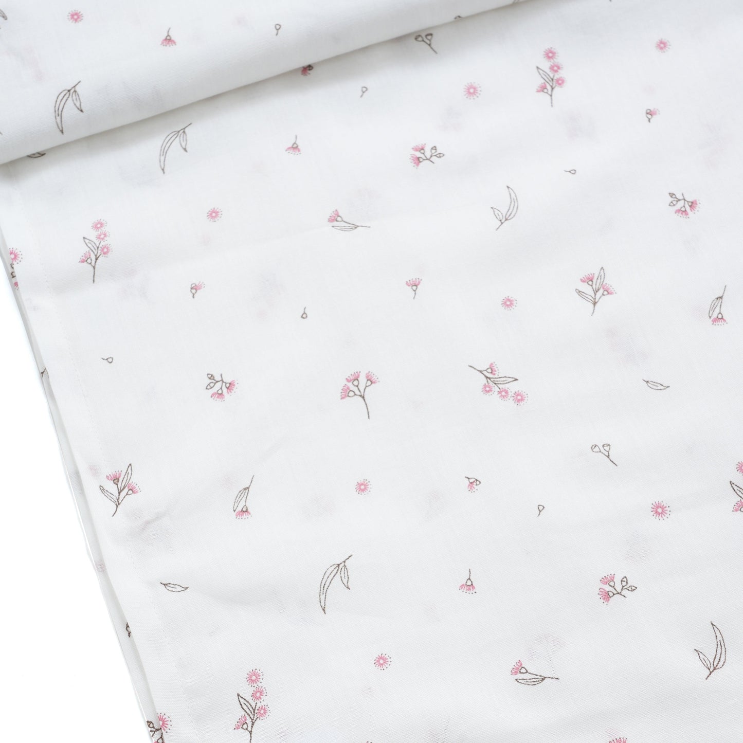 White baby swaddle with delicate small pink floral and leaf pattern, close-up fabric detail