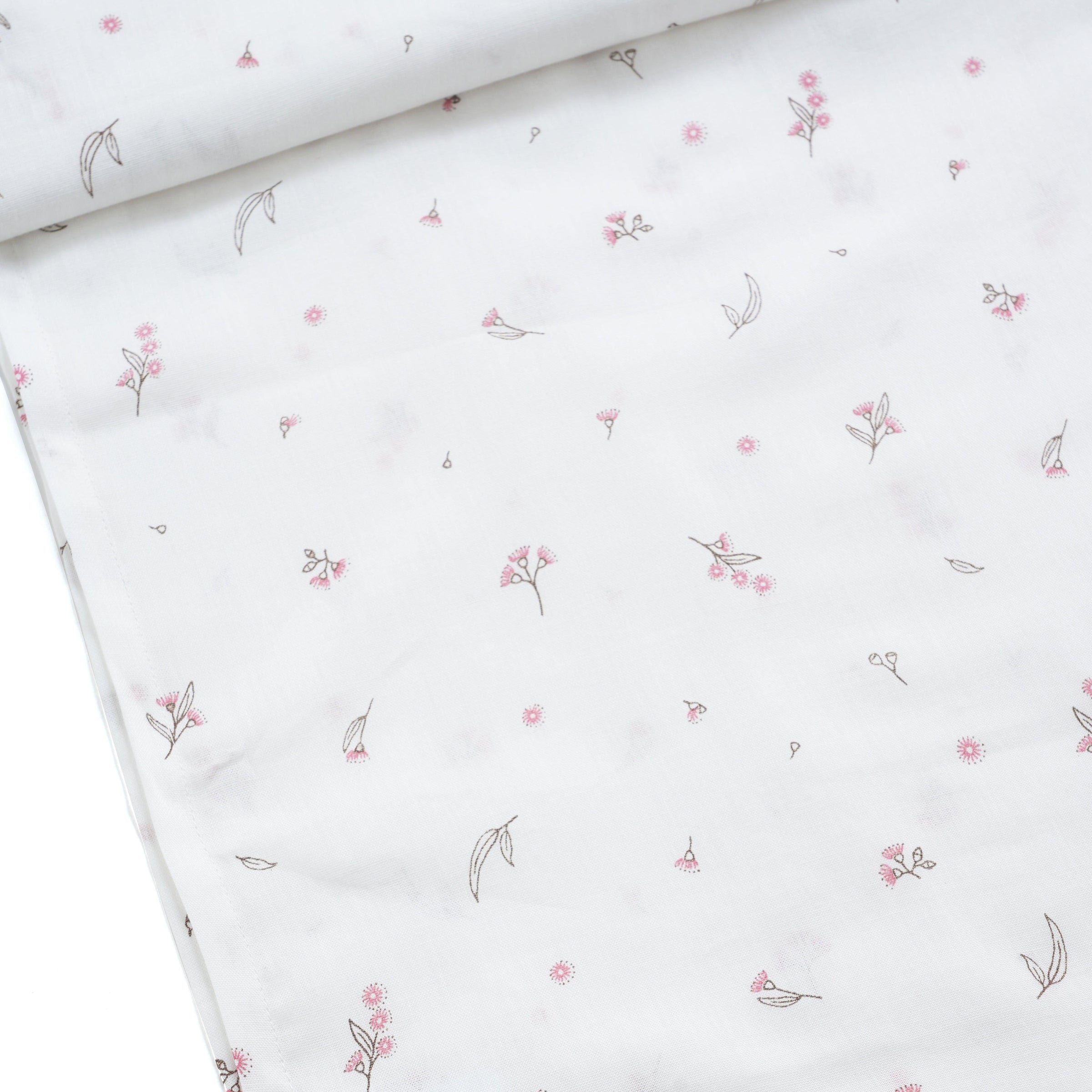 White baby swaddle with delicate small pink floral and leaf pattern, close-up fabric detail