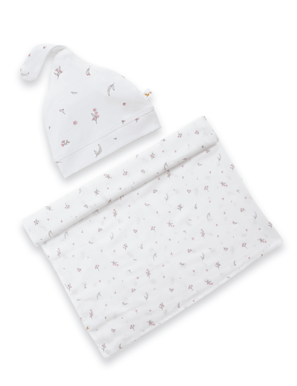 White baby wrap and cap set with delicate pink floral pattern on a plain background