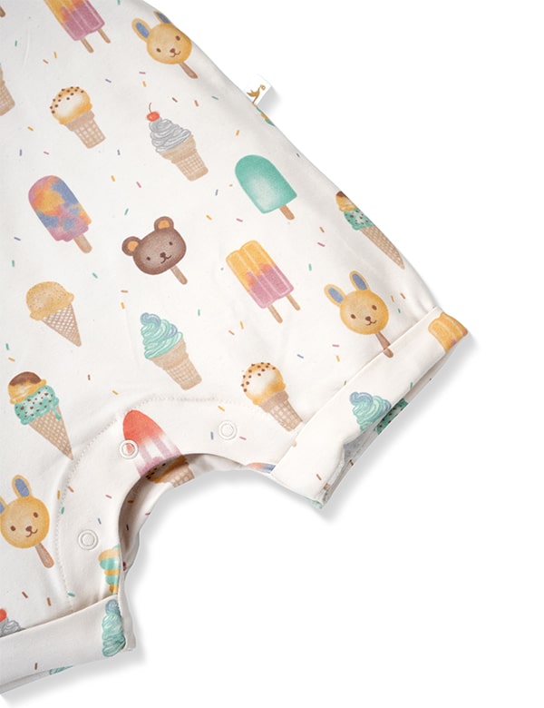 Close-up of a white baby romper with colorful ice cream and animal face popsicle prints and snap buttons