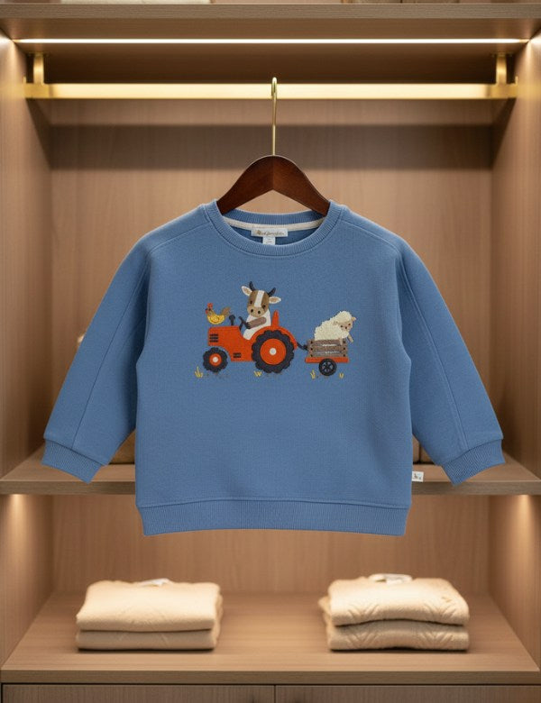 Blue organic cotton children's sweatshirt with tractor and farm animal print hanging in wooden closet